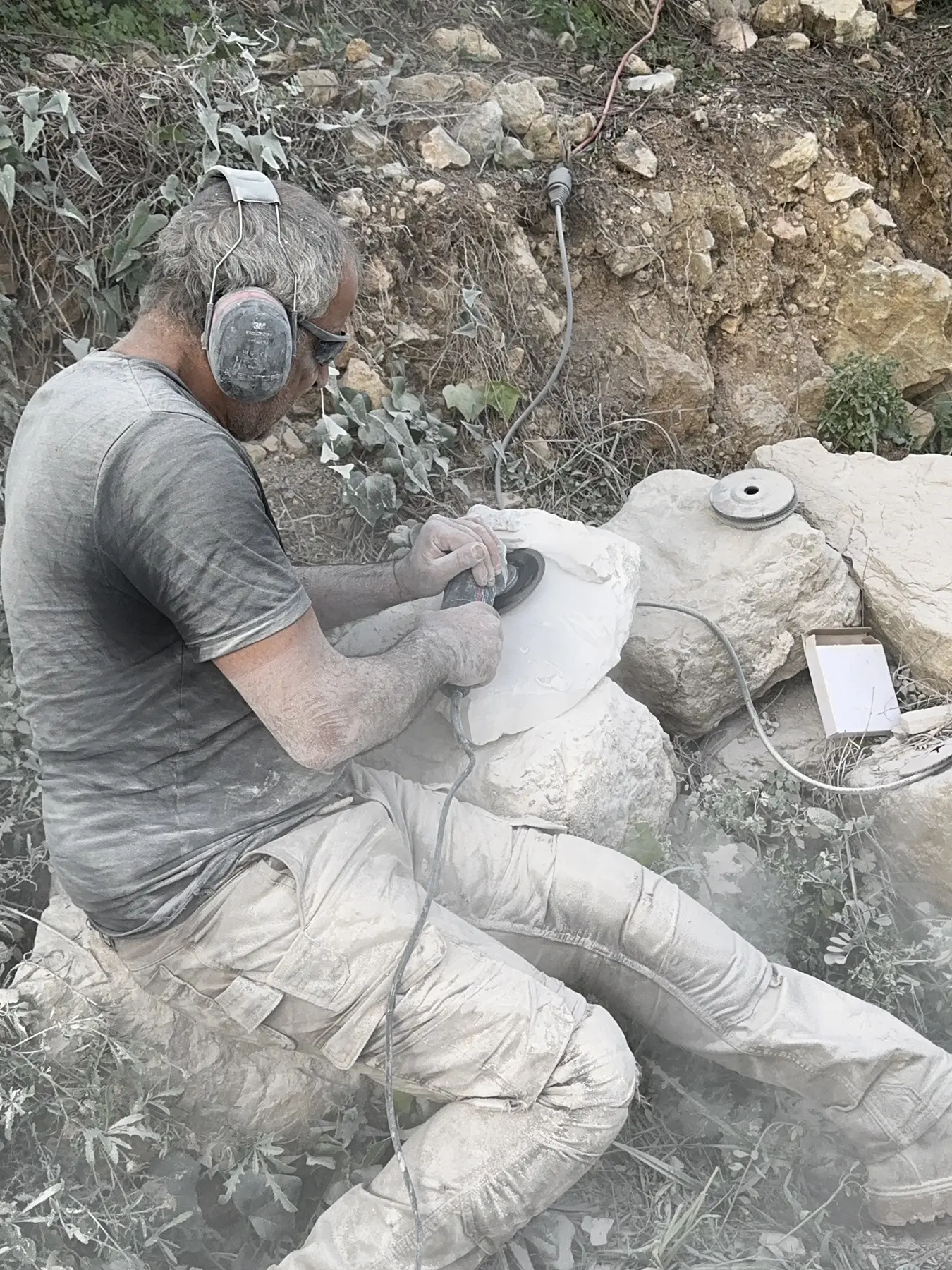 Sculpteur façonnant à la meuleuse les éléments d'un lotus monumental en pierre
